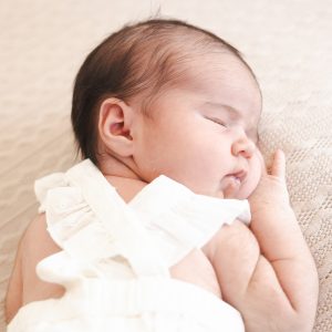 Newborn schlafend in weissem Kleid